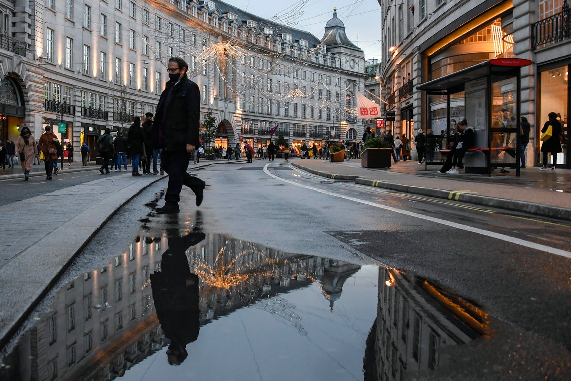 A man wears a face mask while he walks and is reflected into a puddle in Regent Street, ahead of the new Tier-4 restriction measures, in London, Saturday, Dec. 19, 2020. Britain's Prime Minister Boris Johnson says Christmas gatherings cannot go ahead and non-essential shops must close in London and much of southern England as he imposed a new, higher level of coronavirus restrictions to curb rapidly spreading infections.(AP Photo/Alberto Pezzali) A man wears a face mask while he walks and is reflected into a puddle in Regent Street, ahead of the new Tier-4 restriction measures, in London, Saturday, Dec. 19, 2020. Britain's Prime Minister Boris Johnson says Christmas gatherings cannot go ahead and non-essential shops must close in London and much of southern England as he imposed a new, higher level of coronavirus restrictions to curb rapidly spreading infections.(AP Photo/Alberto Pezzali)