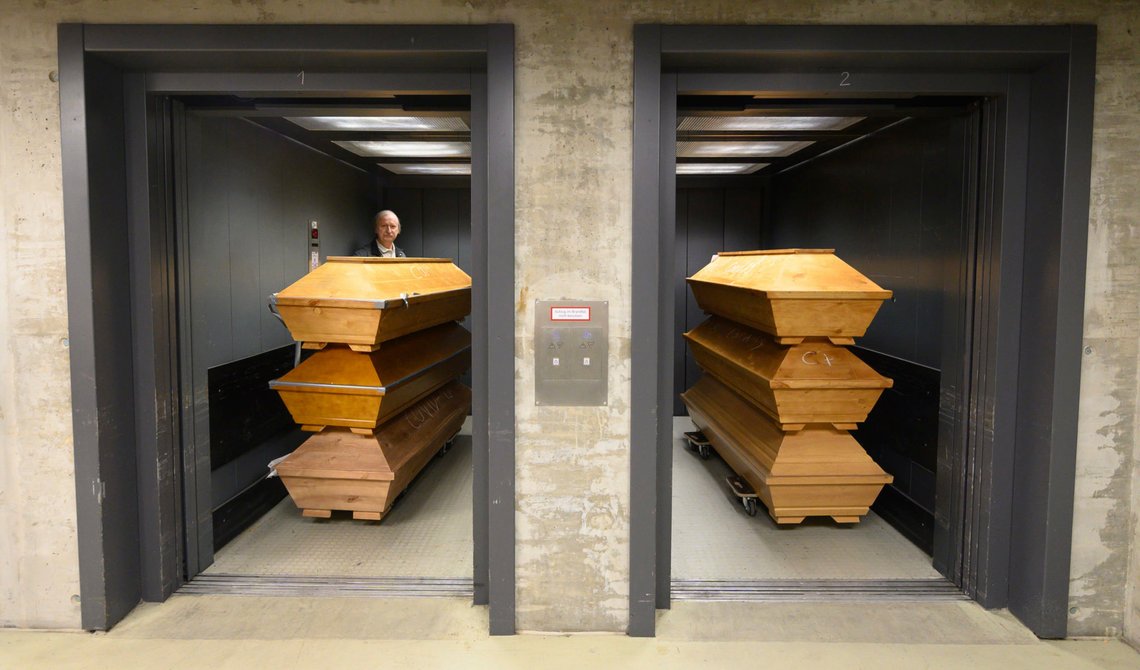 Claus-Dieter Turra, cremator, stands with coffins in an elevator with "Covid-19" chalked on coffins containing a deceased person who died with the coronavirus, with other coffins at the crematorium in Dresden, Germany, Tuesday Dec. 29, 2020. The crematorium has reached the limit of its capacity due to the high mortality in the Corona pandemic and is now dependent on help from other crematoria. (Sebastian Kahnert/dpa via AP) Claus-Dieter Turra, cremator, stands with coffins in an elevator with "Covid-19" chalked on coffins containing a deceased person who died with the coronavirus, with other coffins at the crematorium in Dresden, Germany, Tuesday Dec. 29, 2020. The crematorium has reached the limit of its capacity due to the high mortality in the Corona pandemic and is now dependent on help from other crematoria. (Sebastian Kahnert/dpa via AP)