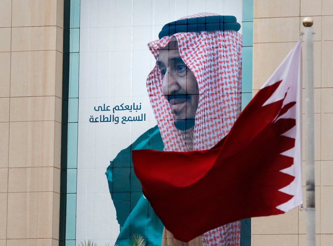 FILE - In this Dec. 9, 2019, file photo, a Qatari flag flies in front of a banner showing Saudi King Salman with Arabic writing that reads, "We pledge you to listen and obey" at a trade center in Riyadh, Saudi Arabia, ahead of the Gulf Cooperation Council "GCC", 40th summit. Kuwait's foreign ministry on Monday, Jan. 4, 2021, announced that Saudi Arabia will lift a years-long embargo on Qatar, opening its air and land borders in the first steps toward ending the Gulf crisis.(AP Photo/Amr Nabil, File) FILE - In this Dec. 9, 2019, file photo, a Qatari flag flies in front of a banner showing Saudi King Salman with Arabic writing that reads, "We pledge you to listen and obey" at a trade center in Riyadh, Saudi Arabia, ahead of the Gulf Cooperation Council "GCC", 40th summit. Kuwait's foreign ministry on Monday, Jan. 4, 2021, announced that Saudi Arabia will lift a years-long embargo on Qatar, opening its air and land borders in the first steps toward ending the Gulf crisis.(AP Photo/Amr Nabil, File)