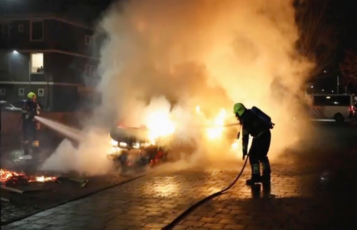 In this grab taken from video on Monday, Jan, 25, 2021, firefighters extinguish a vehicle set on fire by rioters, in Haarlem, Netherlands. Groups of youths have confronted police in several Dutch cities defying the countrys coronavirus curfew and throwing fireworks. Police in the port city of Rotterdam used a water cannon and tear gas in an attempt to disperse a crowd of rioters Monday night. (Mizzle Media via AP) In this grab taken from video on Monday, Jan, 25, 2021, firefighters extinguish a vehicle set on fire by rioters, in Haarlem, Netherlands. Groups of youths have confronted police in several Dutch cities defying the countrys coronavirus curfew and throwing fireworks. Police in the port city of Rotterdam used a water cannon and tear gas in an attempt to disperse a crowd of rioters Monday night. (Mizzle Media via AP)