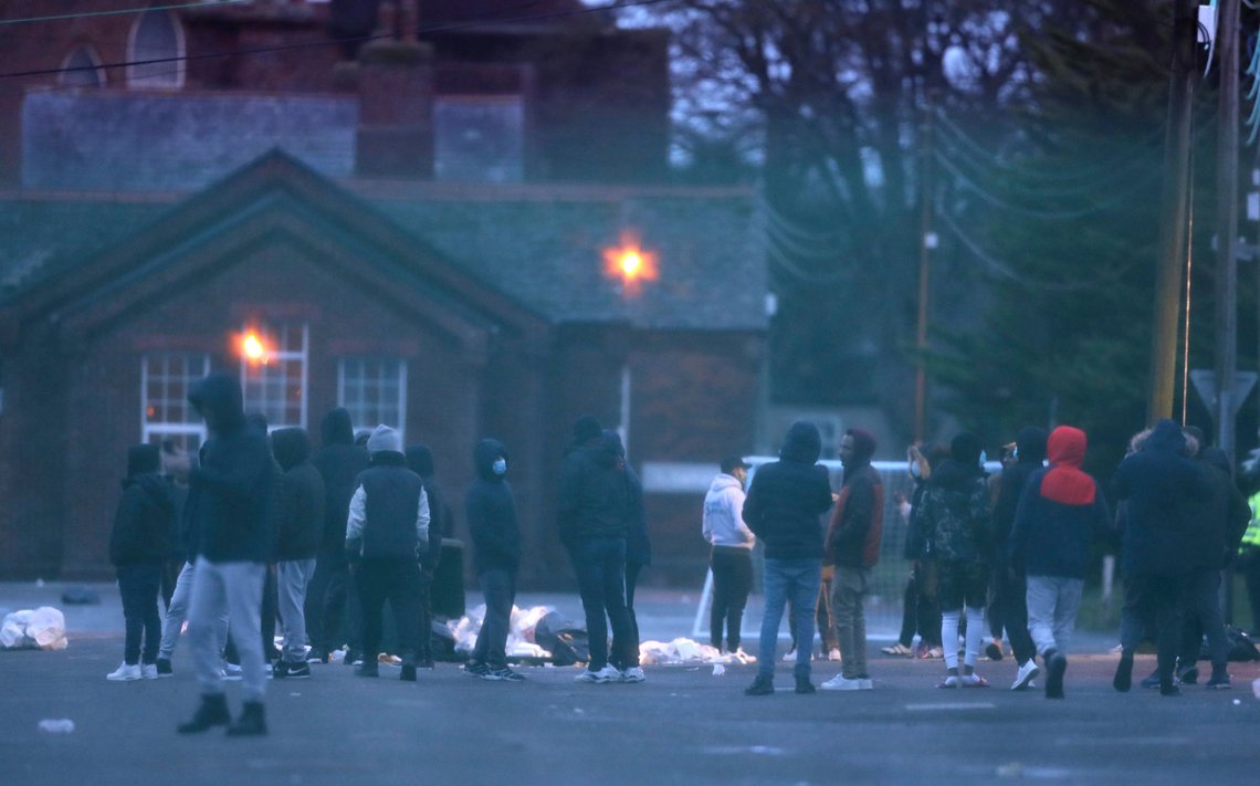 People stand in the open area after a fire broke out at Napier Barracks where asylum seekers are housed in Folkestone, southern England, Friday Jan. 29, 2021. Emergency services attended the incident after a fire broke out at the barracks where some hundreds of asylum seekers have been living, a migrant charity has said. (Gareth Fuller/PA via AP) People stand in the open area after a fire broke out at Napier Barracks where asylum seekers are housed in Folkestone, southern England, Friday Jan. 29, 2021. Emergency services attended the incident after a fire broke out at the barracks where some hundreds of asylum seekers have been living, a migrant charity has said. (Gareth Fuller/PA via AP)