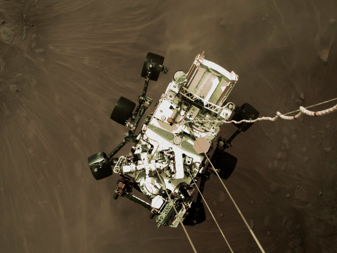 This Thursday, Feb. 18, 2021 photo provided by NASA shows the Perseverance rover lowered towards the surface of Mars during its powered descent. (NASA via AP) This Thursday, Feb. 18, 2021 photo provided by NASA shows the Perseverance rover lowered towards the surface of Mars during its powered descent. (NASA via AP)