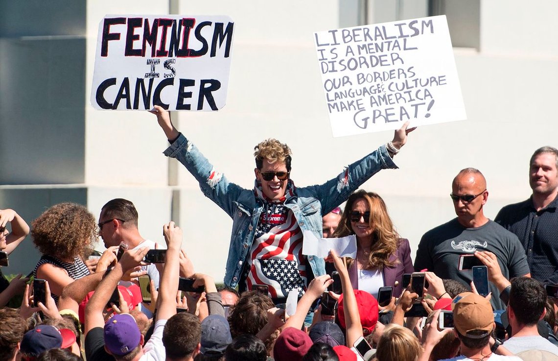 Conservative commentator Milo Yiannopoulos holds up signs to a crowd of supporters on the University of California, Berkeley campus on September 24, 2017.
Although a student group cancelled plans for Free Speech Week, Yiannopoulos was able to speak on campus surrounded by a heavy police presence. / AFP PHOTO / Josh Edelson Conservative commentator Milo Yiannopoulos holds up signs to a crowd of supporters on the University of California, Berkeley campus on September 24, 2017.
Although a student group cancelled plans for Free Speech Week, Yiannopoulos was able to speak on campus surrounded by a heavy police presence. / AFP PHOTO / Josh Edelson