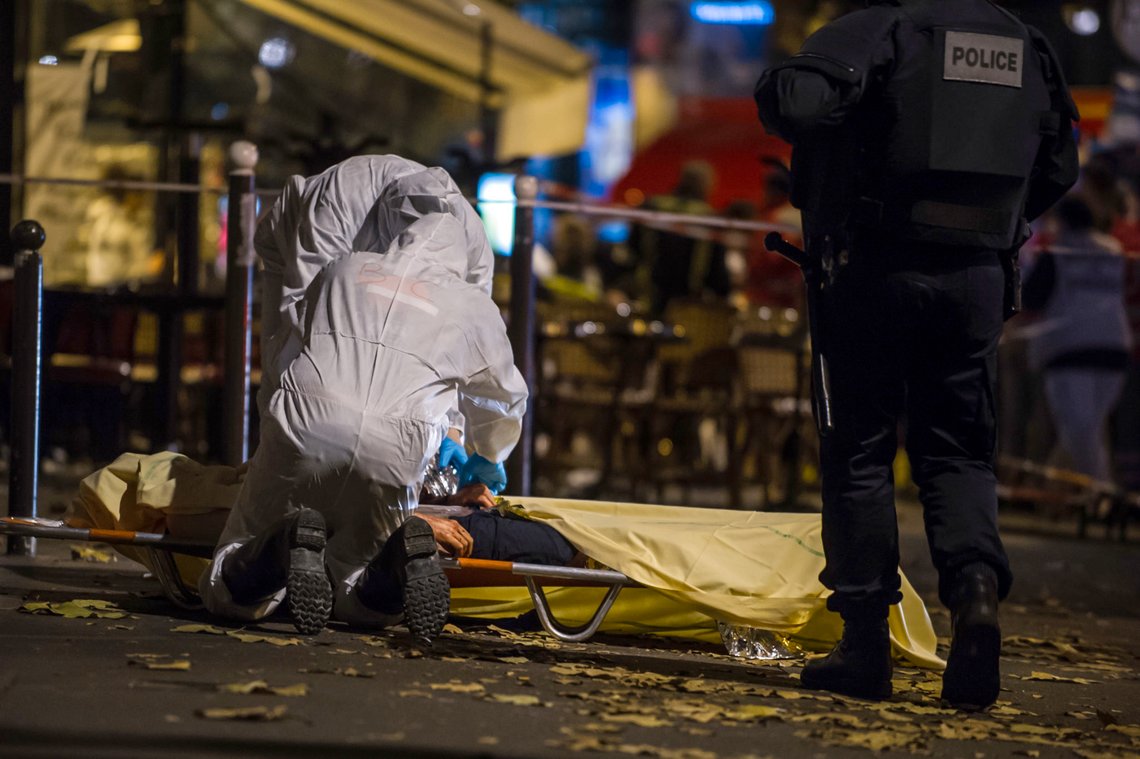 Investigating police officers inspect the lifeless body of a victim of a shooting attack outside the Bataclan concert hall in Paris, France, Saturday, Nov. 14, 2015. Well over 100 people were killed in Paris on Friday night in a series of shooting, explosions. French President Francois Hollande declared a state of emergency and announced that he was closing the country's borders. (AP Photo/Kamil Zihnioglu) Investigating police officers inspect the lifeless body of a victim of a shooting attack outside the Bataclan concert hall in Paris, France, Saturday, Nov. 14, 2015. Well over 100 people were killed in Paris on Friday night in a series of shooting, explosions. French President Francois Hollande declared a state of emergency and announced that he was closing the country's borders. (AP Photo/Kamil Zihnioglu)