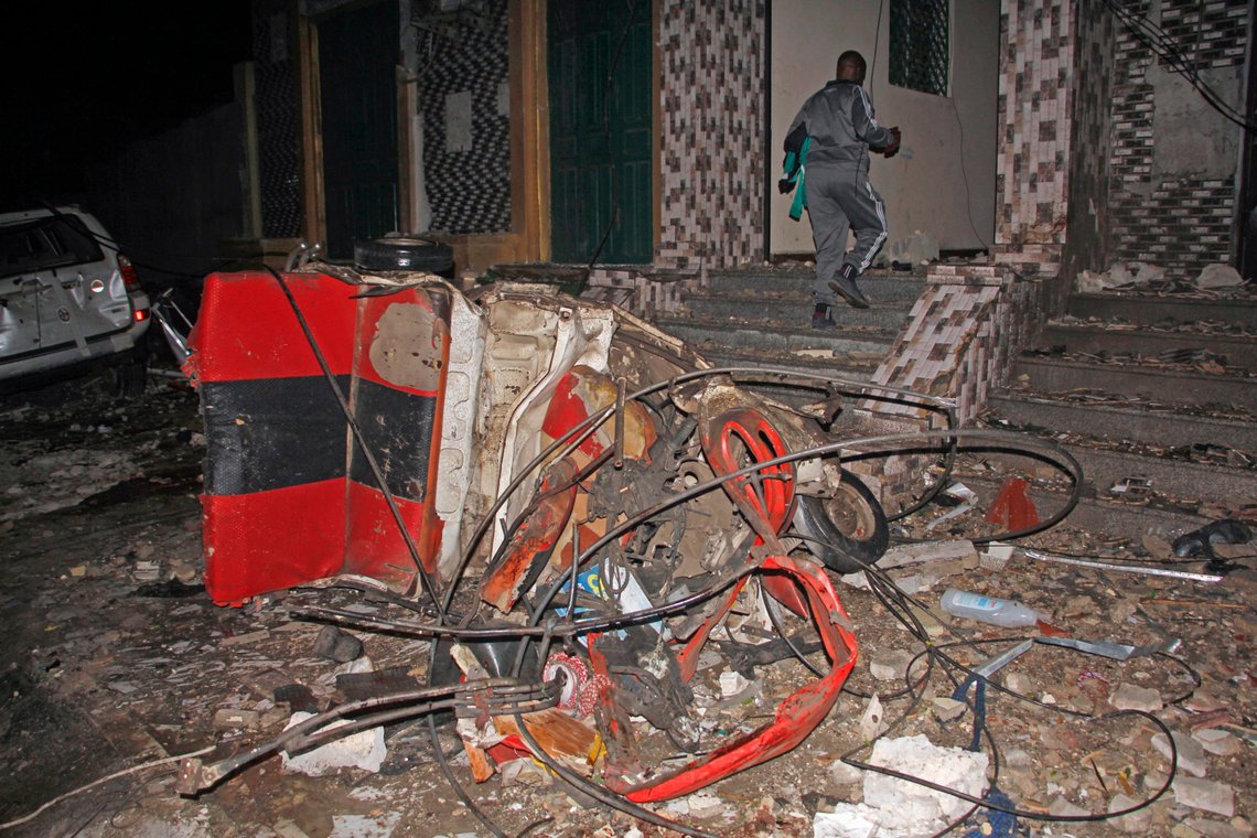 A man walks past a destroyed vehicle at the scene of a blast at a popular restaurant in the capital Mogadishu, Somalia, Friday, March 5, 2021. A car packed with explosives rammed into a popular restaurant in Somalia's capital on Friday night, and police said at least 10 people were killed and more than 30 wounded. (AP Photo/Farah Abdi Warsameh) A man walks past a destroyed vehicle at the scene of a blast at a popular restaurant in the capital Mogadishu, Somalia, Friday, March 5, 2021. A car packed with explosives rammed into a popular restaurant in Somalia's capital on Friday night, and police said at least 10 people were killed and more than 30 wounded. (AP Photo/Farah Abdi Warsameh)