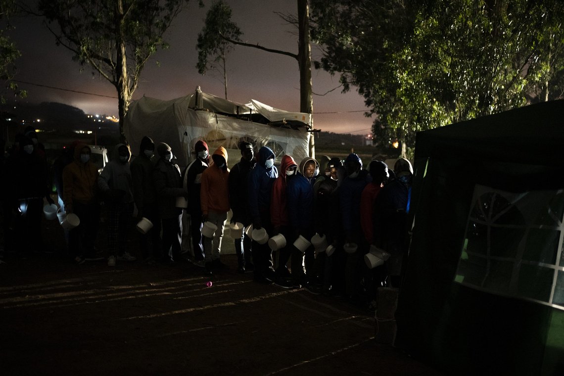 Migrants queue up to receive food in Las Raices camp in San Cristobal de la Laguna, in the Canary Island of Tenerife, Spain, Wednesday, March 17, 2021. Several thousand migrants have arrived on the Spanish archipelago in the first months of 2021. Due to the terrible living conditions and the poor quality of food and water at the Las Raices camp, some migrants have decided to leave the camp and sleep in shacks in a nearby forest instead. (AP Photo/Joan Mateu) Migrants queue up to receive food in Las Raices camp in San Cristobal de la Laguna, in the Canary Island of Tenerife, Spain, Wednesday, March 17, 2021. Several thousand migrants have arrived on the Spanish archipelago in the first months of 2021. Due to the terrible living conditions and the poor quality of food and water at the Las Raices camp, some migrants have decided to leave the camp and sleep in shacks in a nearby forest instead. (AP Photo/Joan Mateu)