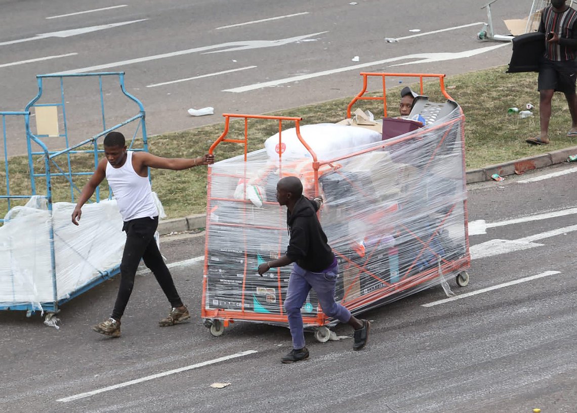 People make their way with good on a trolley from a store in Durban, South Africa, Tuesday July 13, 2021, as ongoing looting and violence continues. South Africa's rioting continued Tuesday with the death toll rising to 32 as police and the military struggle to quell the violence in Gauteng and KwaZulu-Natal provinces. (AP Photo) People make their way with good on a trolley from a store in Durban, South Africa, Tuesday July 13, 2021, as ongoing looting and violence continues. South Africa's rioting continued Tuesday with the death toll rising to 32 as police and the military struggle to quell the violence in Gauteng and KwaZulu-Natal provinces. (AP Photo)