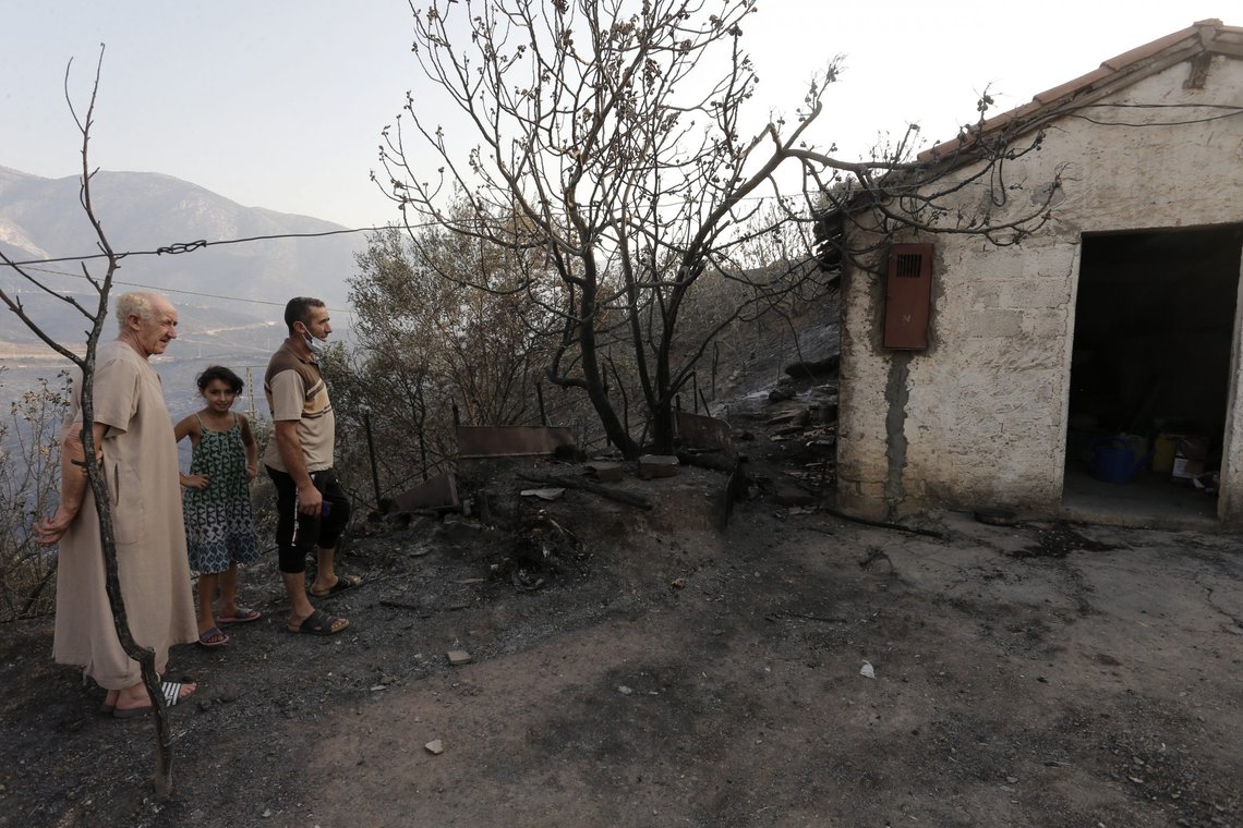 A family watches a house near charred trees in the village of Achlouf, in the Kabyle region, east of Algiers, Friday, Aug.13, 2021. Dozens of fires began devouring forested mountainsides in the Berber region of Kabyle Monday. The President declared a three-day mourning period to honor the lives lost. (AP Photo/Toufik Doudou) A family watches a house near charred trees in the village of Achlouf, in the Kabyle region, east of Algiers, Friday, Aug.13, 2021. Dozens of fires began devouring forested mountainsides in the Berber region of Kabyle Monday. The President declared a three-day mourning period to honor the lives lost. (AP Photo/Toufik Doudou)