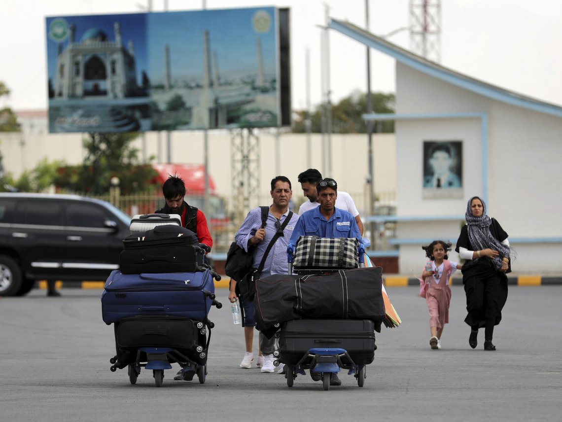 Passengers walk to the departures terminal of Hamid Karzai International Airport in Kabul, Afghanistan, Saturday, Aug. 14, 2021. As a Taliban offensive encircles the Afghan capital, there's increasingly only one way out for those fleeing the war, and only one way in for U.S. troops sent to protect American diplomats still on the ground: the airport. (AP Photo/Rahmat Gul) Passengers walk to the departures terminal of Hamid Karzai International Airport in Kabul, Afghanistan, Saturday, Aug. 14, 2021. As a Taliban offensive encircles the Afghan capital, there's increasingly only one way out for those fleeing the war, and only one way in for U.S. troops sent to protect American diplomats still on the ground: the airport. (AP Photo/Rahmat Gul)