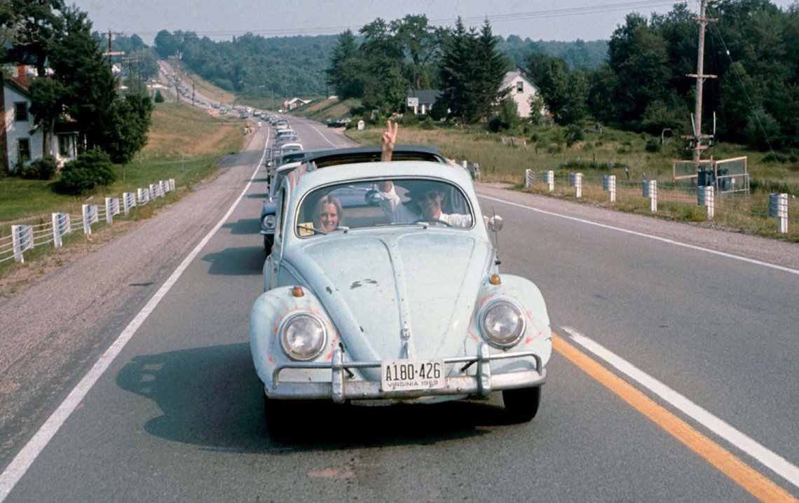 A man drives a Volkswagen Beetle ahead of a long line of cars on the way to the Woodstock Music & Art Fair while flashing a peace sign through the sunroof of the car, in Bethel, New York, in August 1969. A man drives a Volkswagen Beetle ahead of a long line of cars on the way to the Woodstock Music & Art Fair while flashing a peace sign through the sunroof of the car, in Bethel, New York, in August 1969.