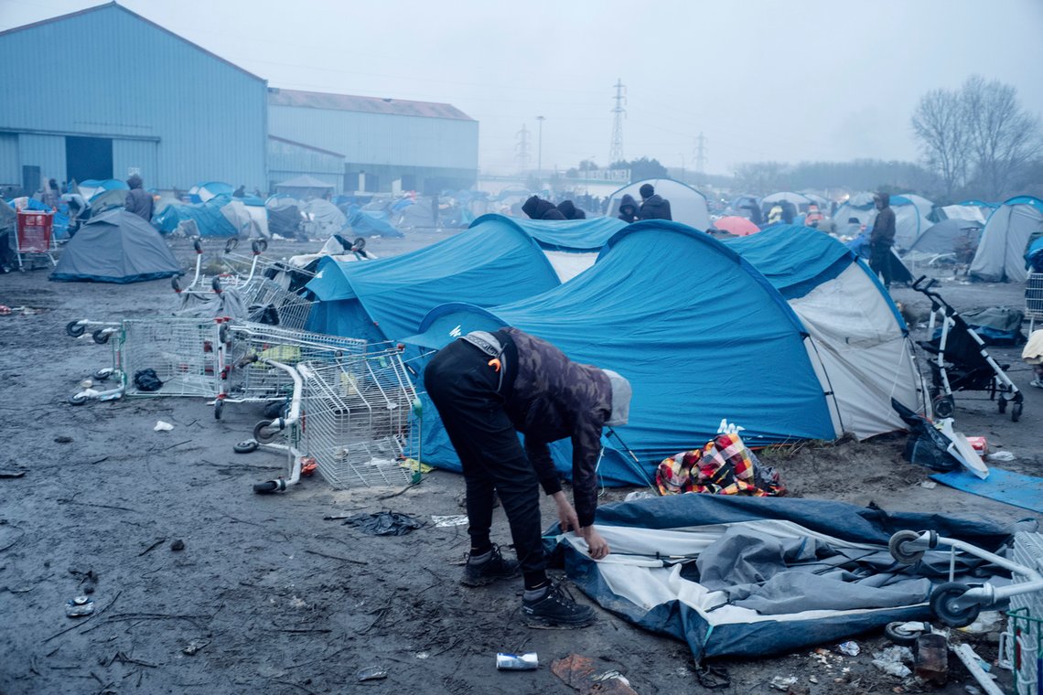 Fransk politi evakuerer en illegal migrantleir nær Dunkirk. Bildet viser en migrant som pakker sammen teltet sitt. Foto: AP /Louis Witter/ NTB Fransk politi evakuerer en illegal migrantleir nær Dunkirk. Bildet viser en migrant som pakker sammen teltet sitt. Foto: AP /Louis Witter/ NTB
