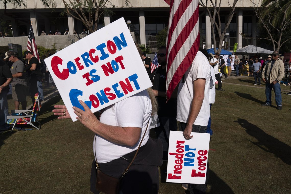 A woman uses a sign to shield herself from the sun while attending a rally held to protest the city's new COVID-19 vaccine mandate in Los Angeles Monday, Nov. 8, 2021, in Los Angeles. Starting Monday, anyone going to a shopping mall, theater, gym or nail salon in Los Angeles must verify they are vaccinated against COVID-19. The mandate, among the strictest in the country, requires proof of shots for everyone entering a wide variety of businesses. (AP Photo/Jae C. Hong) A woman uses a sign to shield herself from the sun while attending a rally held to protest the city's new COVID-19 vaccine mandate in Los Angeles Monday, Nov. 8, 2021, in Los Angeles. Starting Monday, anyone going to a shopping mall, theater, gym or nail salon in Los Angeles must verify they are vaccinated against COVID-19. The mandate, among the strictest in the country, requires proof of shots for everyone entering a wide variety of businesses. (AP Photo/Jae C. Hong)