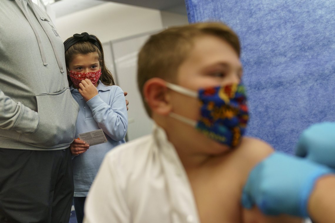 Michael Farias, left, holds his daughter, McKenzie, 8, as she watches her brother, Mikey, 10, receive the Pfizer COVID-19 vaccine for children ages 5-11 at a state-run site in Cranston, R.I., Thursday, Nov. 4, 2021. (AP Photo/David Goldman) Michael Farias, left, holds his daughter, McKenzie, 8, as she watches her brother, Mikey, 10, receive the Pfizer COVID-19 vaccine for children ages 5-11 at a state-run site in Cranston, R.I., Thursday, Nov. 4, 2021. (AP Photo/David Goldman)