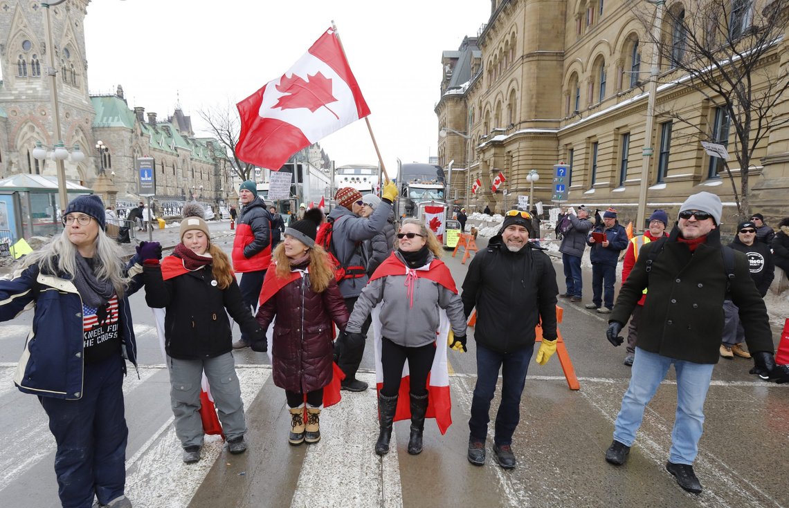 People hold hands in front of Parliament Hill as a rally against COVID-19 restrictions, which began as a cross-country convoy protesting a federal vaccine mandate for truckers, continues in Ottawa on Wednesday, Feb. 9, 2022. (Patrick Doyle/The Canadian Press via AP) People hold hands in front of Parliament Hill as a rally against COVID-19 restrictions, which began as a cross-country convoy protesting a federal vaccine mandate for truckers, continues in Ottawa on Wednesday, Feb. 9, 2022. (Patrick Doyle/The Canadian Press via AP)