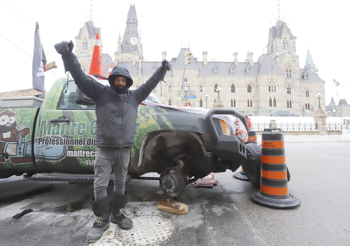 A man who removed the tires from his pickup truck stands in front of West Block on Parliament Hill as a rally against COVID-19 restrictions, which began as a cross-country convoy protesting a federal vaccine mandate for truckers, continues in Ottawa, Canada, Monday, Jan. 31, 2022. (Patrick Doyle/The Canadian Press via AP) A man who removed the tires from his pickup truck stands in front of West Block on Parliament Hill as a rally against COVID-19 restrictions, which began as a cross-country convoy protesting a federal vaccine mandate for truckers, continues in Ottawa, Canada, Monday, Jan. 31, 2022. (Patrick Doyle/The Canadian Press via AP)