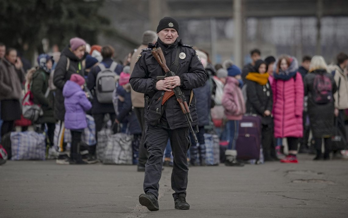 A Ukrainian police officer carrying an assault rifle walks on a platform backdropped by people waiting for a Kiev bound train in Kostiantynivka, Donetsk region, eastern Ukraine, Thursday, Feb. 24, 2022. Russia launched a wide-ranging attack on Ukraine on Thursday, hitting cities and bases with airstrikes or shelling, as civilians piled into trains and cars to flee. (AP Photo/Vadim Ghirda) A Ukrainian police officer carrying an assault rifle walks on a platform backdropped by people waiting for a Kiev bound train in Kostiantynivka, Donetsk region, eastern Ukraine, Thursday, Feb. 24, 2022. Russia launched a wide-ranging attack on Ukraine on Thursday, hitting cities and bases with airstrikes or shelling, as civilians piled into trains and cars to flee. (AP Photo/Vadim Ghirda)