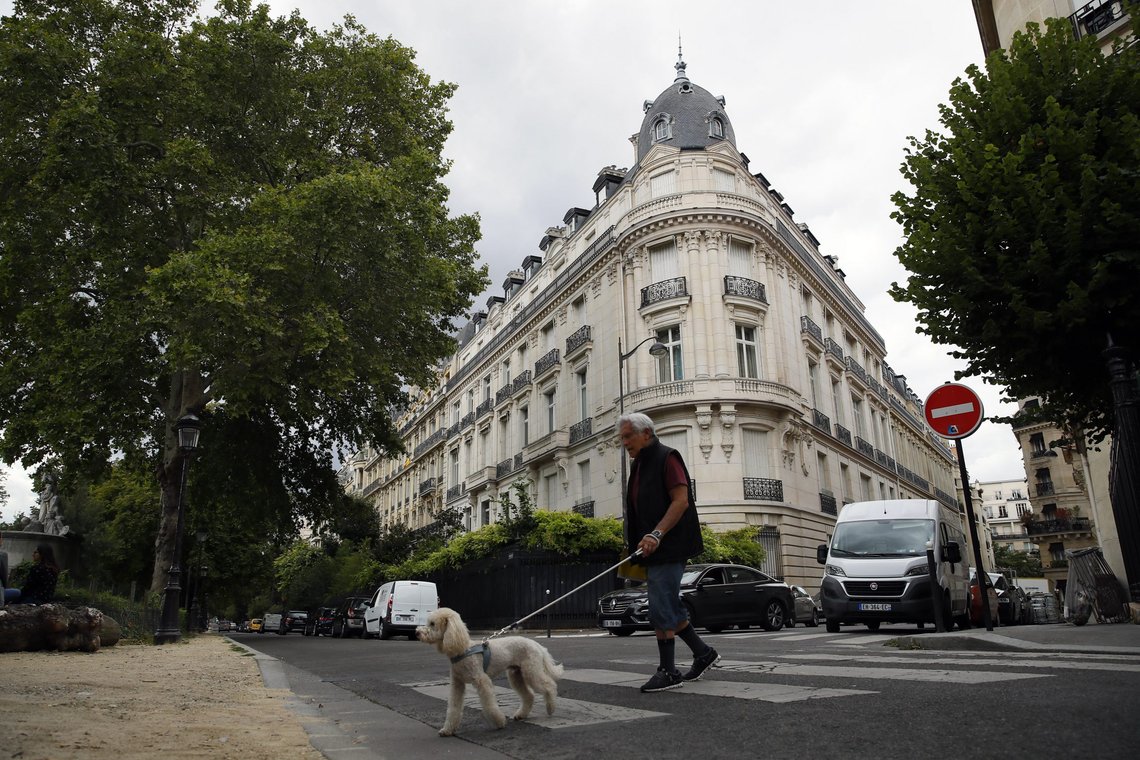 FILE - In this Aug.13, 2019 file photo, a man walks his dog next to an apartment building owned by Jeffrey Epstein in Paris. Modeling agent Jean-Luc Brunel who was close to U.S. financier Jeffrey Epstein has been taken into custody in France, suspected of an array of crimes, including the rape of minors and trafficking minors for sexual exploitation, Paris prosecutors said Thursday. The prosecutors' office said Jean-Luc Brunel was detained for questioning on Wednesday. (AP Photo/Francois Mori, File) FILE - In this Aug.13, 2019 file photo, a man walks his dog next to an apartment building owned by Jeffrey Epstein in Paris. Modeling agent Jean-Luc Brunel who was close to U.S. financier Jeffrey Epstein has been taken into custody in France, suspected of an array of crimes, including the rape of minors and trafficking minors for sexual exploitation, Paris prosecutors said Thursday. The prosecutors' office said Jean-Luc Brunel was detained for questioning on Wednesday. (AP Photo/Francois Mori, File)