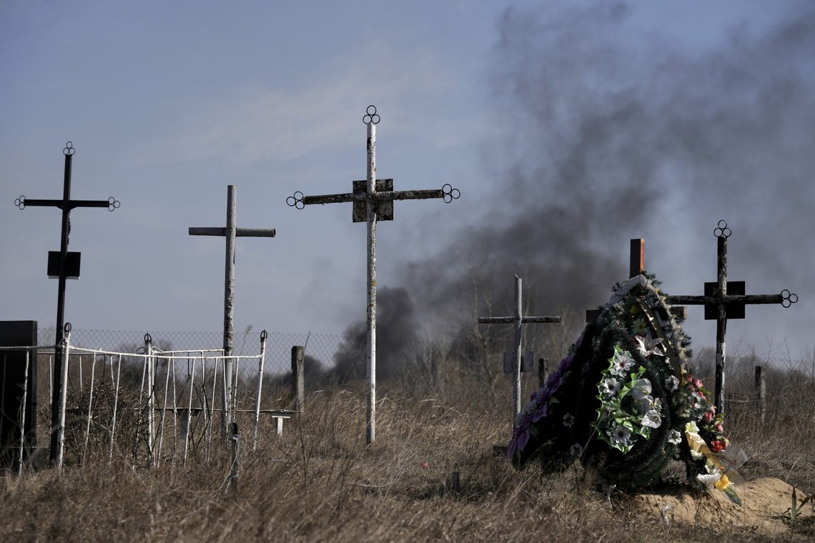 A smoke from shelling rises as a wreath of flowers is placed at a cemetery in Vasylkiv south west of Kyiv, Ukraine, Saturday, March 12, 2022. Russian forces appeared to make progress from northeast Ukraine in their slow fight to reach the capital, Kyiv, while tanks and artillery pounded places already under siege. (AP Photo/Vadim Ghirda) A smoke from shelling rises as a wreath of flowers is placed at a cemetery in Vasylkiv south west of Kyiv, Ukraine, Saturday, March 12, 2022. Russian forces appeared to make progress from northeast Ukraine in their slow fight to reach the capital, Kyiv, while tanks and artillery pounded places already under siege. (AP Photo/Vadim Ghirda)