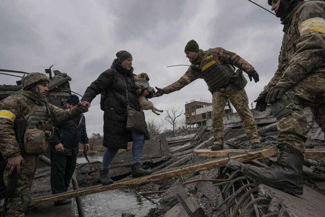 Ukrainian servicemen help a woman carrying a small dog cross the Irpin river on an improvised path under a bridge, that was destroyed by Ukrainian troops designed to slow any Russian military advance, while assisting people fleeing the town of Irpin, Ukraine, Saturday, March 5, 2022. What looked like a breakthrough cease-fire to evacuate residents from two cities in Ukraine quickly fell apart Saturday as Ukrainian officials said shelling had halted the work to remove civilians hours after Russia announced the deal. (AP Photo/Vadim Ghirda) Ukrainian servicemen help a woman carrying a small dog cross the Irpin river on an improvised path under a bridge, that was destroyed by Ukrainian troops designed to slow any Russian military advance, while assisting people fleeing the town of Irpin, Ukraine, Saturday, March 5, 2022. What looked like a breakthrough cease-fire to evacuate residents from two cities in Ukraine quickly fell apart Saturday as Ukrainian officials said shelling had halted the work to remove civilians hours after Russia announced the deal. (AP Photo/Vadim Ghirda)