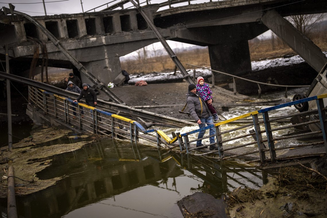 Local militiaman Valery, 37, carries a child as he helps a fleeing family across a bridge destroyed by artillery, on the outskirts of Kyiv, Ukraine, Wednesday, March 2. 2022. Russian forces have escalated their attacks on crowded cities in what Ukraine's leader called a blatant campaign of terror. (AP Photo/Emilio Morenatti) Local militiaman Valery, 37, carries a child as he helps a fleeing family across a bridge destroyed by artillery, on the outskirts of Kyiv, Ukraine, Wednesday, March 2. 2022. Russian forces have escalated their attacks on crowded cities in what Ukraine's leader called a blatant campaign of terror. (AP Photo/Emilio Morenatti)