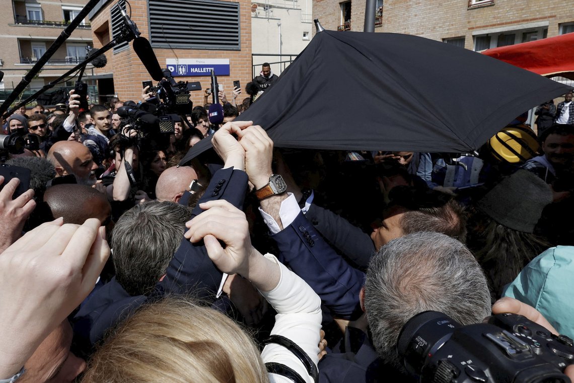 Macrons sikkerhetsvakter løfter en paraply over presidenten etter at det ble kastet cherrytomater mot ham. Foto: Benoit Tessier /Pool via AP / NTB Macrons sikkerhetsvakter løfter en paraply over presidenten etter at det ble kastet cherrytomater mot ham. Foto: Benoit Tessier /Pool via AP / NTB