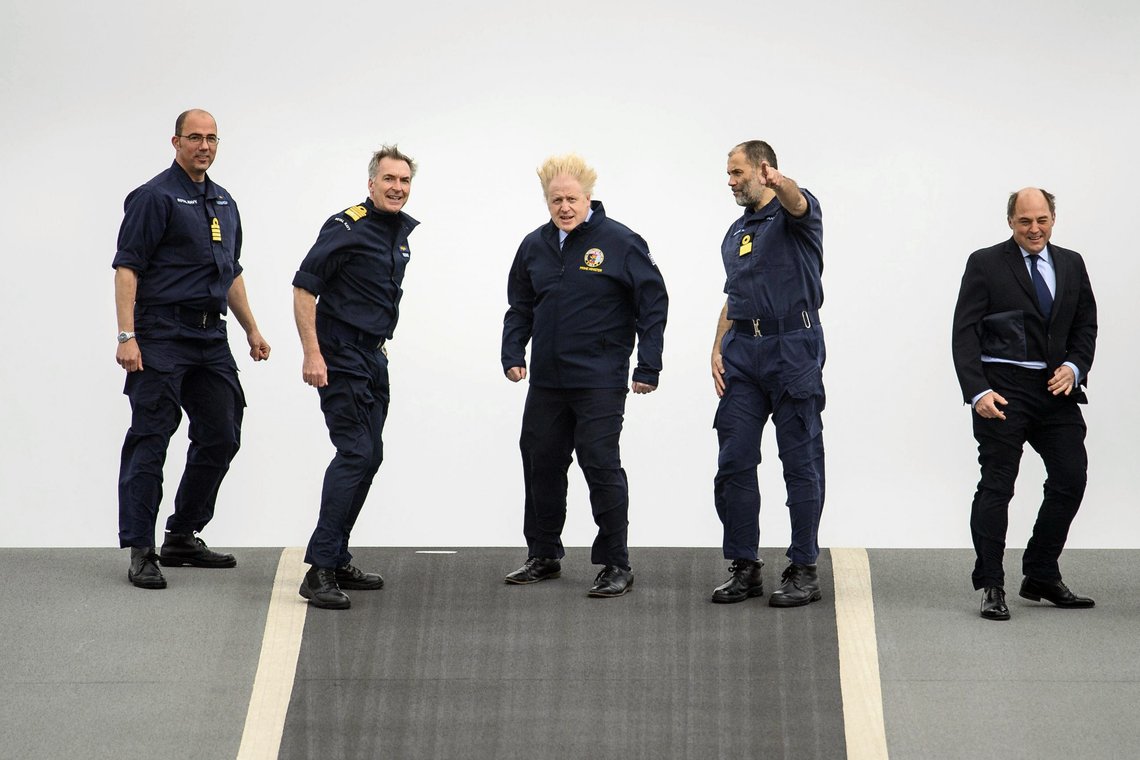 From left, Captain Angus Essenhigh, First Sea Lord Admiral Tony Radakin, Prime Minister Boris Johnson, Commodore Steve Moorhouse and Defence Secretary Ben Wallace face strong winds as they walk on the flight deck, during a visit aboard HMS Queen Elizabeth in Portsmouth, England, Friday, May 21, 2021 ahead of its first operational deployment to the Far East. (Leon Neal/Pool Photo via AP) From left, Captain Angus Essenhigh, First Sea Lord Admiral Tony Radakin, Prime Minister Boris Johnson, Commodore Steve Moorhouse and Defence Secretary Ben Wallace face strong winds as they walk on the flight deck, during a visit aboard HMS Queen Elizabeth in Portsmouth, England, Friday, May 21, 2021 ahead of its first operational deployment to the Far East. (Leon Neal/Pool Photo via AP)