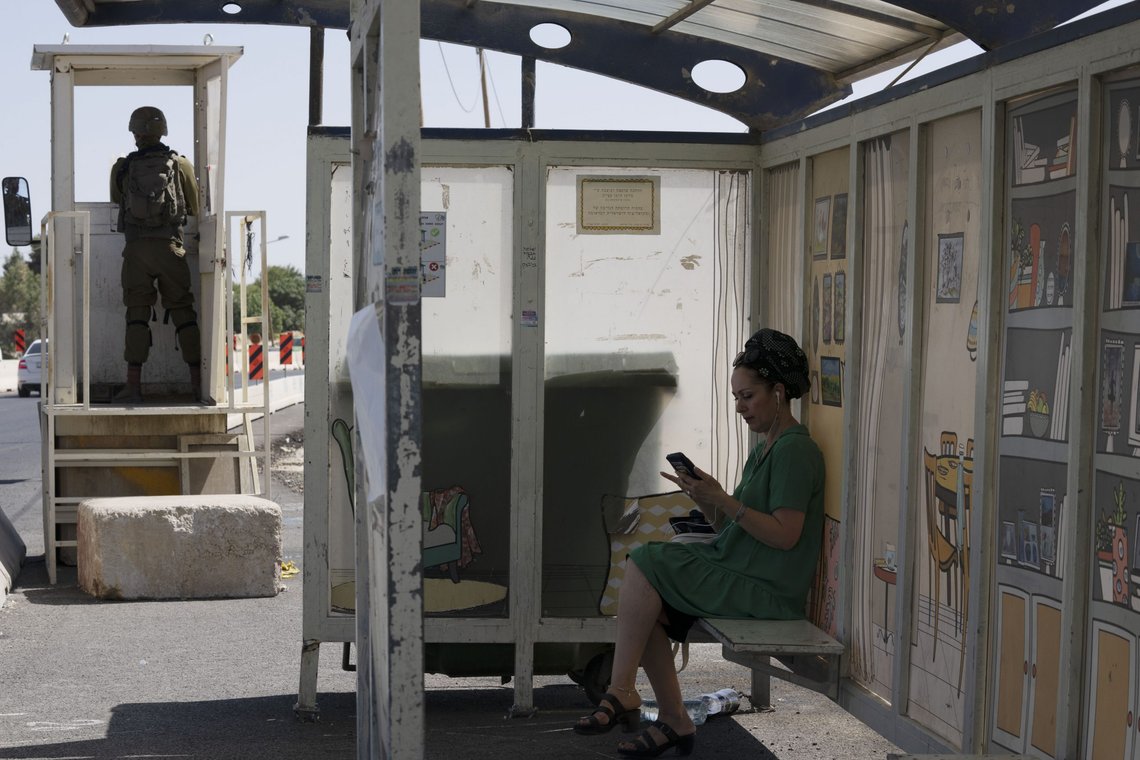 An Israeli soldier stands guard at a bus stop as a woman waits for a bus at the Gush Etzion junction, the transportation hub for a number of West Bank Jewish settlements, Thursday, June 9, 2022. Israeli settlers in the occupied West Bank may soon have a taste of the military rule that Palestinians have been living under for 55 years. A looming end-of-month deadline to extend legal protections to Jewish settlers has put Israel’s government on the brink of collapse and drawn widespread warnings that the territory could be plunged into chaos. (AP Photo/Maya Alleruzzo) An Israeli soldier stands guard at a bus stop as a woman waits for a bus at the Gush Etzion junction, the transportation hub for a number of West Bank Jewish settlements, Thursday, June 9, 2022. Israeli settlers in the occupied West Bank may soon have a taste of the military rule that Palestinians have been living under for 55 years. A looming end-of-month deadline to extend legal protections to Jewish settlers has put Israel’s government on the brink of collapse and drawn widespread warnings that the territory could be plunged into chaos. (AP Photo/Maya Alleruzzo)