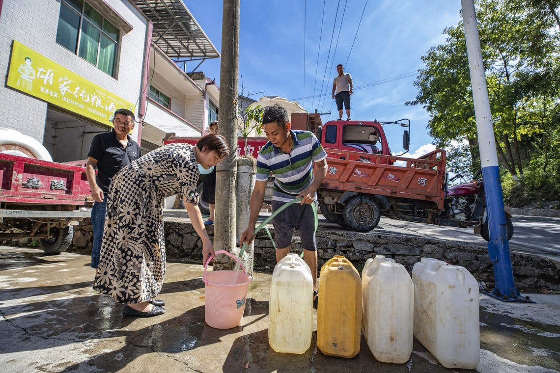 In this photo released by Xinhua News Agency, a worker stands on top of a truck distributing water to residents with a banner which reads "Luoping Drought Relief water truck" in Luoping village of Wushan County in southwestern China's Chongqing, Saturday, Aug. 13, 2022. Unusually high temperatures and a prolonged drought are affecting large swaths of China, affecting crop yields and drinking water supplies for thousands of people. (Huang Wei/Xinhua via AP) In this photo released by Xinhua News Agency, a worker stands on top of a truck distributing water to residents with a banner which reads "Luoping Drought Relief water truck" in Luoping village of Wushan County in southwestern China's Chongqing, Saturday, Aug. 13, 2022. Unusually high temperatures and a prolonged drought are affecting large swaths of China, affecting crop yields and drinking water supplies for thousands of people. (Huang Wei/Xinhua via AP)