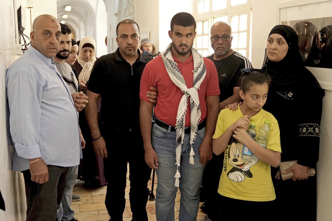 Relatives of Muhammad Shaham, a Palestinian who was killed in an Israeli police raid on Monday, stand in the corridor of a court that is holding a hearing in Shaham's case, in east Jerusalem, Wednesday, Aug. 17, 2022. Israeli police shot and killed Shaham claiming he had attempted to stab officers during a raid in the the Kafr Aqab area of east Jerusalem. Ibrahim al-Shaham denied that his son attempted to stab the officers, and said that the police found no weapons in the home. (AP Photo/ Mahmoud Illean) Relatives of Muhammad Shaham, a Palestinian who was killed in an Israeli police raid on Monday, stand in the corridor of a court that is holding a hearing in Shaham's case, in east Jerusalem, Wednesday, Aug. 17, 2022. Israeli police shot and killed Shaham claiming he had attempted to stab officers during a raid in the the Kafr Aqab area of east Jerusalem. Ibrahim al-Shaham denied that his son attempted to stab the officers, and said that the police found no weapons in the home. (AP Photo/ Mahmoud Illean)