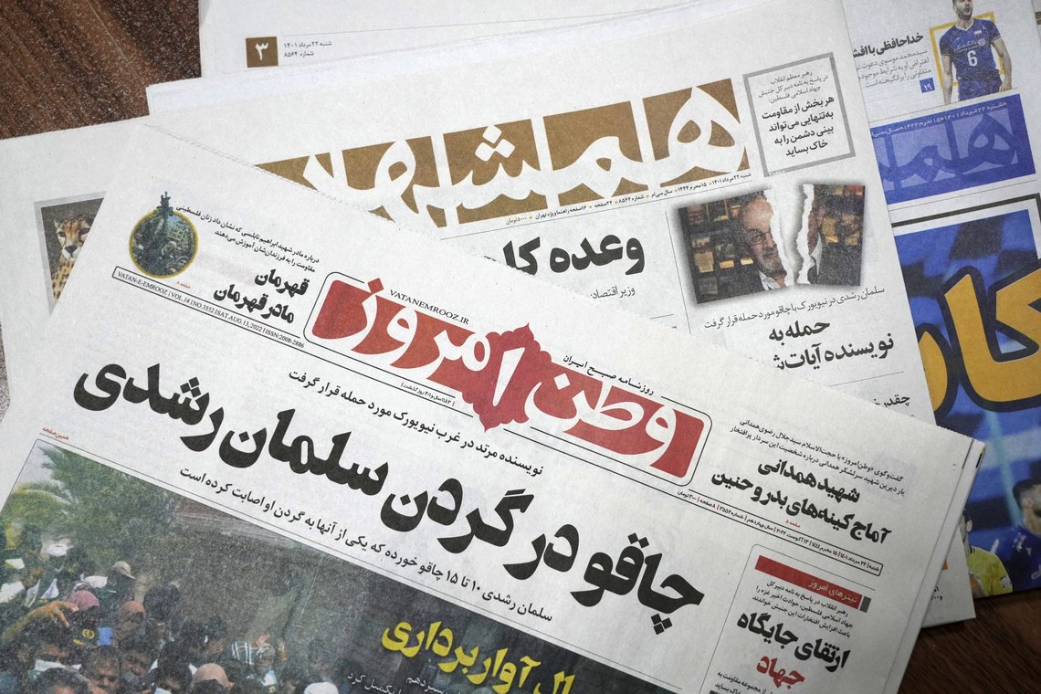 The front pages of the Aug. 13 edition of the Iranian newspapers, Vatan-e Emrooz, front, with title reading in Farsi: "Knife in the neck of Salman Rushdie," and Hamshahri, rear, with title: "Attack on writer of Satanic Verses," are pictured in Tehran Saturday, Aug. 13, 2022. Rushdie, whose novel “The Satanic Verses” drew death threats from Iran’s leader in the 1980s, was stabbed in the neck and abdomen Friday by a man who rushed the stage as the author was about to give a lecture in western New York. (AP Photo/Vahid Salemi) The front pages of the Aug. 13 edition of the Iranian newspapers, Vatan-e Emrooz, front, with title reading in Farsi: "Knife in the neck of Salman Rushdie," and Hamshahri, rear, with title: "Attack on writer of Satanic Verses," are pictured in Tehran Saturday, Aug. 13, 2022. Rushdie, whose novel “The Satanic Verses” drew death threats from Iran’s leader in the 1980s, was stabbed in the neck and abdomen Friday by a man who rushed the stage as the author was about to give a lecture in western New York. (AP Photo/Vahid Salemi)