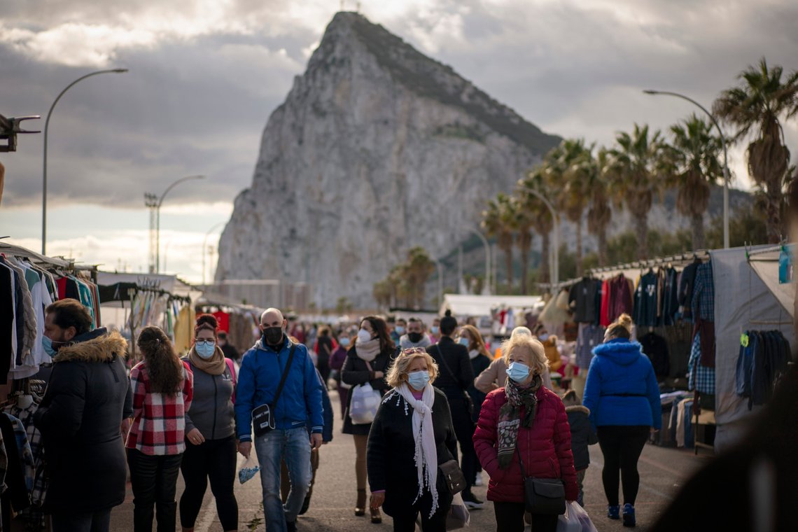 Backdropped by the Gibraltar rock, people walk along the stalls of a weekly market at the Spanish city of La Linea on Monday, Jan. 4, 2021. Fears of disruptions following Britain's departure from the European Union were replaced by coronavirus-related restrictions on border traffic between Spain and Gibraltar on Monday, the first working day at the United Kingdom's only land border with the European mainland. (AP Photo/Emilio Morenatti) Backdropped by the Gibraltar rock, people walk along the stalls of a weekly market at the Spanish city of La Linea on Monday, Jan. 4, 2021. Fears of disruptions following Britain's departure from the European Union were replaced by coronavirus-related restrictions on border traffic between Spain and Gibraltar on Monday, the first working day at the United Kingdom's only land border with the European mainland. (AP Photo/Emilio Morenatti)