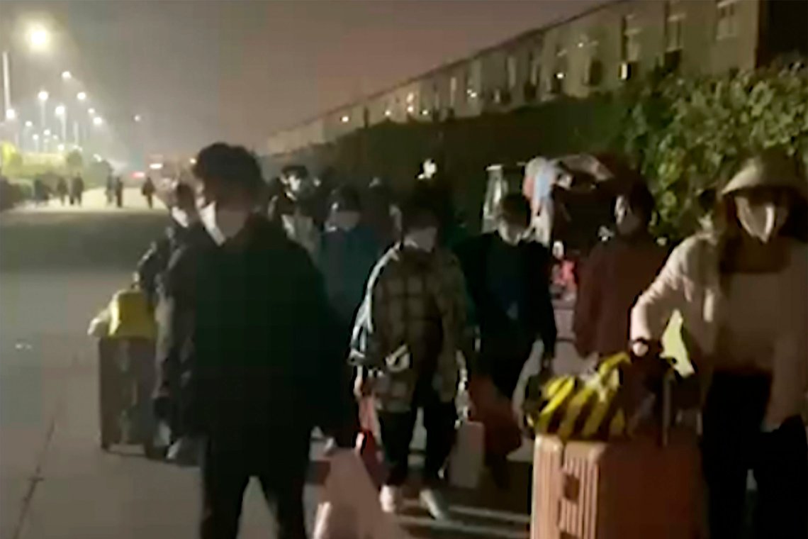 Bildet er hentet fra et videoopptak utgitt av Hangpai Xingyang. Her sees folk med kofferter og vesker som forlater et Foxconn-anlegg i Zhengzhou. Kina. Foto: Hangpai Xingyang / AP / NTB Bildet er hentet fra et videoopptak utgitt av Hangpai Xingyang. Her sees folk med kofferter og vesker som forlater et Foxconn-anlegg i Zhengzhou. Kina. Foto: Hangpai Xingyang / AP / NTB