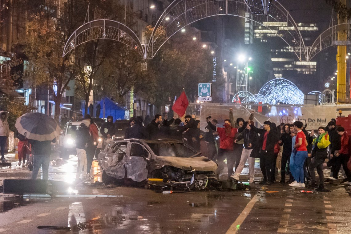 Moroccan soccer supporters cheer as they stand next to a burned out car in Brussels, Sunday, Nov. 27, 2022. Police had to seal off parts of the center of Brussels and moved in with water cannons and tear gas to disperse crowds following violence during and after Morocco's 2-0 win over Belgium at the World Cup. (AP Photo/Geert Vanden Wijngaert) Moroccan soccer supporters cheer as they stand next to a burned out car in Brussels, Sunday, Nov. 27, 2022. Police had to seal off parts of the center of Brussels and moved in with water cannons and tear gas to disperse crowds following violence during and after Morocco's 2-0 win over Belgium at the World Cup. (AP Photo/Geert Vanden Wijngaert)