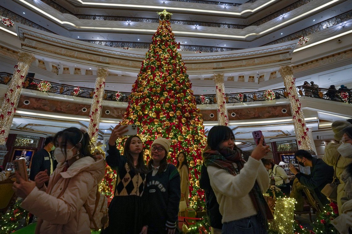 Visitors, some wearing face masks, gather to take souvenir pictures with a giant Christmas tree decorated at a hotel on the eve of Christmas in Beijing, Saturday, Dec. 24, 2022. (AP Photo/Andy Wong) Visitors, some wearing face masks, gather to take souvenir pictures with a giant Christmas tree decorated at a hotel on the eve of Christmas in Beijing, Saturday, Dec. 24, 2022. (AP Photo/Andy Wong)