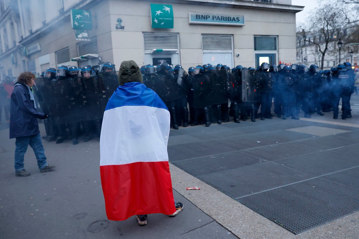 A demonstrator faces riot police officers during a demonstration against pension changes, Thursday, Jan. 19, 2023 in Paris. Workers in many French cities took to the streets Thursday to reject proposed pension changes that would push back the retirement age, amid a day of nationwide strikes and protests seen as a major test for Emmanuel Macron and his presidency. (AP Photo/Lewis Joly) A demonstrator faces riot police officers during a demonstration against pension changes, Thursday, Jan. 19, 2023 in Paris. Workers in many French cities took to the streets Thursday to reject proposed pension changes that would push back the retirement age, amid a day of nationwide strikes and protests seen as a major test for Emmanuel Macron and his presidency. (AP Photo/Lewis Joly)