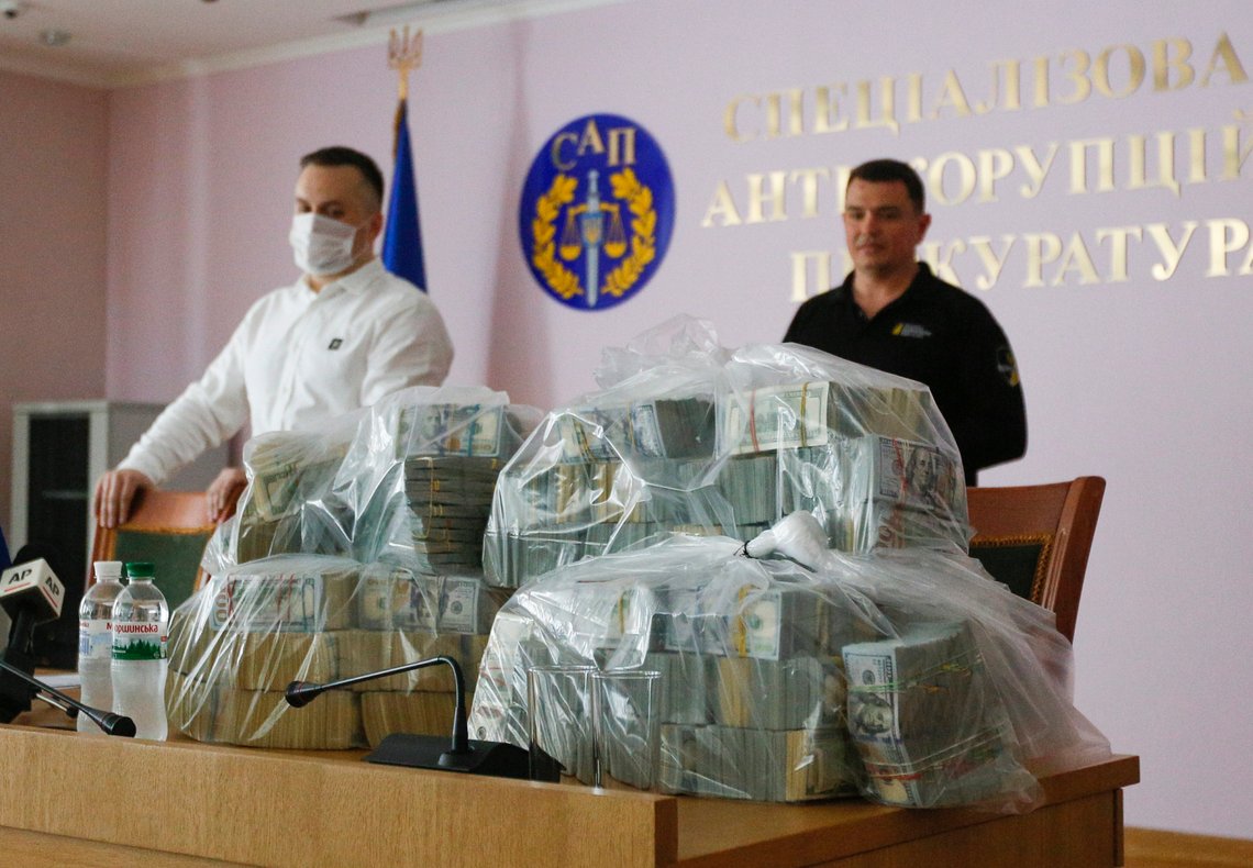 Ukraine's Anti-Corruption Prosecutor Nazar Kholodnytsky, left, and National Anti-Corruption Bureau chief Artem Sytnik at a pile of USD 6 million in plastic bags during a briefing in an anti-corruption prosecutor's office in Kyiv, Ukraine, Saturday, June 13, 2020. Ukrainian authorities say they have intercepted a USD 6 million bribe attempt at dropping a criminal investigation against the head of the Burisma natural gas company where former US Vice President Joe Biden's son once held a board seat. (AP Photo/Efrem Lukatsky) Ukraine's Anti-Corruption Prosecutor Nazar Kholodnytsky, left, and National Anti-Corruption Bureau chief Artem Sytnik at a pile of USD 6 million in plastic bags during a briefing in an anti-corruption prosecutor's office in Kyiv, Ukraine, Saturday, June 13, 2020. Ukrainian authorities say they have intercepted a USD 6 million bribe attempt at dropping a criminal investigation against the head of the Burisma natural gas company where former US Vice President Joe Biden's son once held a board seat. (AP Photo/Efrem Lukatsky)