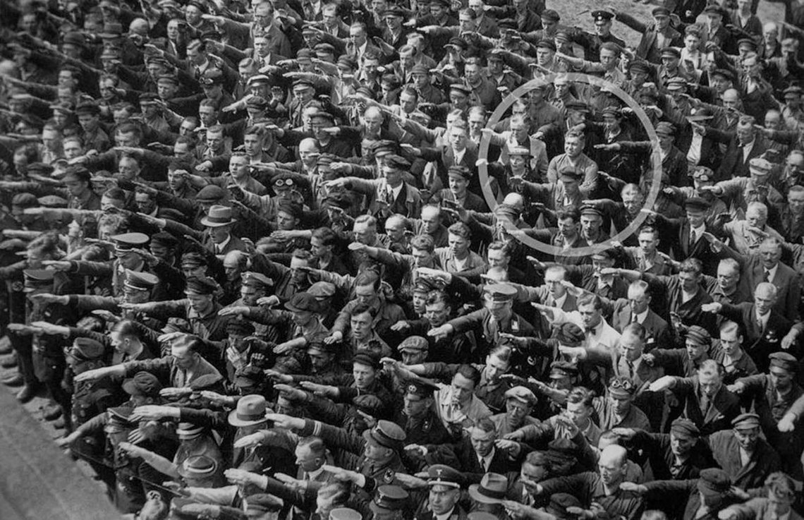Bildet ble tatt ved sjøsettingen av et tysk hærfartøy i 1936, under en seremoni som Adolf Hitler selv deltok.
Inne i bildet sto en enslig mann med armene i kors mens hundrevis av menn og kvinner rundt ham holdt armene opp i honnør og troskap til Nazipartiet og dets leder, Adolf Hitler. Alle tilstedeværende viser sin udødelige støtte til Der Führer ved å kaste ut deres aller beste «Sieg Heil».
August Landmesser, som grimaserte med armene i kors, sto sterk og trassig da han viste sin misbilligelse ved ikke å vise støtte til nazipartiet. Bildet ble tatt ved sjøsettingen av et tysk hærfartøy i 1936, under en seremoni som Adolf Hitler selv deltok.
Inne i bildet sto en enslig mann med armene i kors mens hundrevis av menn og kvinner rundt ham holdt armene opp i honnør og troskap til Nazipartiet og dets leder, Adolf Hitler. Alle tilstedeværende viser sin udødelige støtte til Der Führer ved å kaste ut deres aller beste «Sieg Heil».
August Landmesser, som grimaserte med armene i kors, sto sterk og trassig da han viste sin misbilligelse ved ikke å vise støtte til nazipartiet.