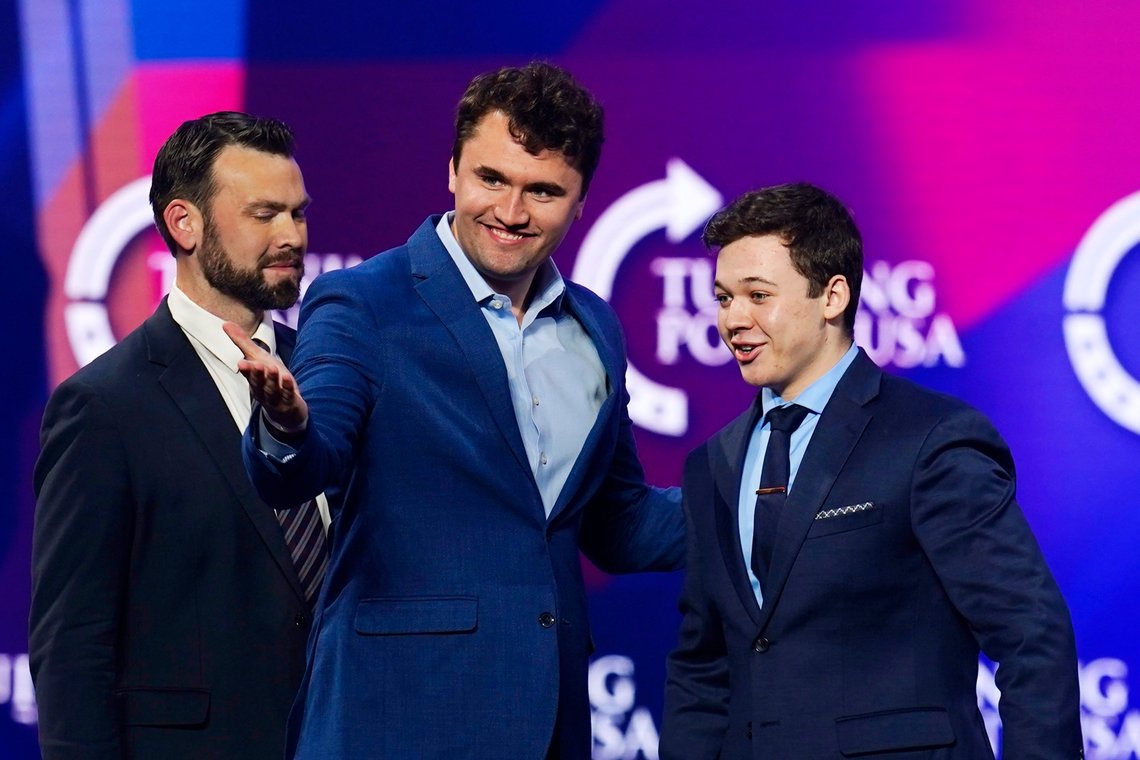 Kyle Rittenhouse, right, is introduced to a cheering crowd by Charlie Kirk, middle, founder of Turning Point USA, as Jack Posobiec, left, host of Once America News Network, joins them on stage at a panel discussion at the Turning Point USA America Fest 2021 event, Monday, Dec. 20, 2021, in Phoenix. The panel discussion, called "Kenosha On Camera," comes a month after Rittenhouse's acquittal on charges in the deadly Kenosha shootings in 2020. (AP Photo/Ross D. Franklin) Kyle Rittenhouse, right, is introduced to a cheering crowd by Charlie Kirk, middle, founder of Turning Point USA, as Jack Posobiec, left, host of Once America News Network, joins them on stage at a panel discussion at the Turning Point USA America Fest 2021 event, Monday, Dec. 20, 2021, in Phoenix. The panel discussion, called "Kenosha On Camera," comes a month after Rittenhouse's acquittal on charges in the deadly Kenosha shootings in 2020. (AP Photo/Ross D. Franklin)