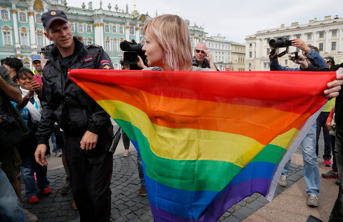 En politibetjent snakker med en aktivist for homofiles rettigheter som står med et regnbueflagg foran journalister under en protestaksjon på Dvortsovaya (Palass) plass i St. Petersburg, Russland, 2. august 2015. Russlands president Vladimir Putin signerte ny lovgivning mandag 24. juli 2023, som markerte det endelige skrittet mot å kriminalisere kjønnsbekreftende prosedyrer, et knusende slag mot Russlands allerede hardt pressede LGBTQ+-samfunn. Foto: AP/Dmitry Lovetsky En politibetjent snakker med en aktivist for homofiles rettigheter som står med et regnbueflagg foran journalister under en protestaksjon på Dvortsovaya (Palass) plass i St. Petersburg, Russland, 2. august 2015. Russlands president Vladimir Putin signerte ny lovgivning mandag 24. juli 2023, som markerte det endelige skrittet mot å kriminalisere kjønnsbekreftende prosedyrer, et knusende slag mot Russlands allerede hardt pressede LGBTQ+-samfunn. Foto: AP/Dmitry Lovetsky
