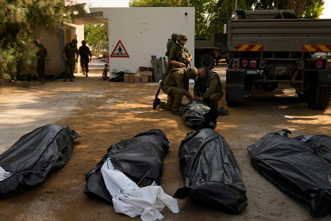 Israeli soldiers stand next to the bodies of Israelis killed by Hamas militants in kibbutz Kfar Azza on Tuesday, Oct. 10, 2023. Hamas militants overran Kfar Azza on Saturday, where many Israelis were killed and taken captive. (AP Photo/Ohad Zwigenberg) Israeli soldiers stand next to the bodies of Israelis killed by Hamas militants in kibbutz Kfar Azza on Tuesday, Oct. 10, 2023. Hamas militants overran Kfar Azza on Saturday, where many Israelis were killed and taken captive. (AP Photo/Ohad Zwigenberg)