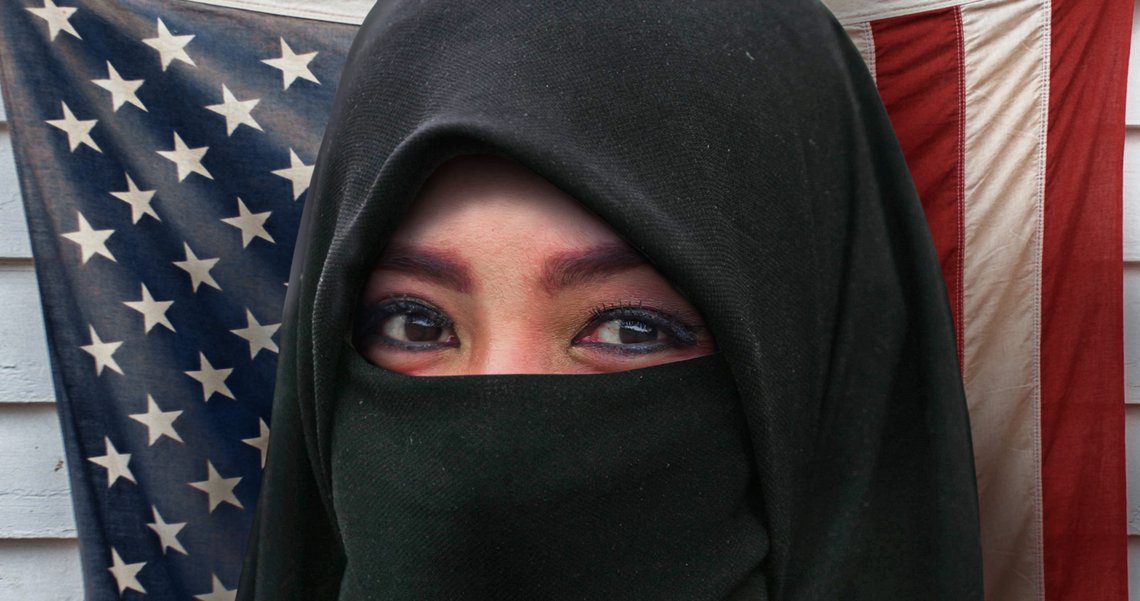 Muslim woman in traditional Islam burqa or burka head scarf posing cheerful and happy smiling. United States American flag background in diversity and culture contrast. Shutterstock by TheVisualsYouNeed, Spain. Muslim woman in traditional Islam burqa or burka head scarf posing cheerful and happy smiling. United States American flag background in diversity and culture contrast. Shutterstock by TheVisualsYouNeed, Spain.