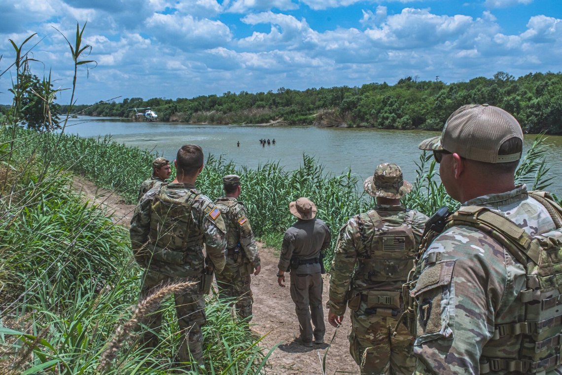 Members of the Texas National Guard watch a Border Patrol helicopter hover above a group of civilians wading in the Rio Grande along the Texas-Mexico border during Operation Lone Star.
24 May 2023 Members of the Texas National Guard watch a Border Patrol helicopter hover above a group of civilians wading in the Rio Grande along the Texas-Mexico border during Operation Lone Star.
24 May 2023