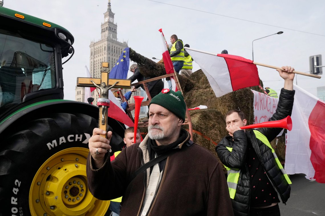 Polish farmers with national flags and angry slogans written on boards, protest against European Union green policies that trim their production and against cheap grain and other food imports from Ukraine, in Warsaw, Poland, on Tuesday, Feb. 27, 2024. Farmers have been protesting for weeks across the EU. (AP Photo/Czarek Sokolowski) Polish farmers with national flags and angry slogans written on boards, protest against European Union green policies that trim their production and against cheap grain and other food imports from Ukraine, in Warsaw, Poland, on Tuesday, Feb. 27, 2024. Farmers have been protesting for weeks across the EU. (AP Photo/Czarek Sokolowski)