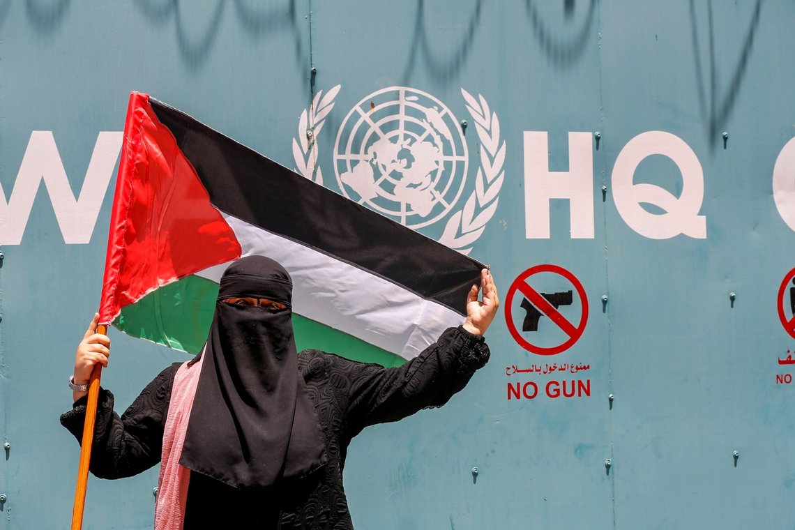 Palestinian refugees gather with national flags outside the United Nations Relief and Works Agency (UNRWA) in Gaza City on June 20, 2023, to protest cuts in aid. Photo: Shutterstock by Anas-Mohammed. Palestine. Palestinian refugees gather with national flags outside the United Nations Relief and Works Agency (UNRWA) in Gaza City on June 20, 2023, to protest cuts in aid. Photo: Shutterstock by Anas-Mohammed. Palestine.