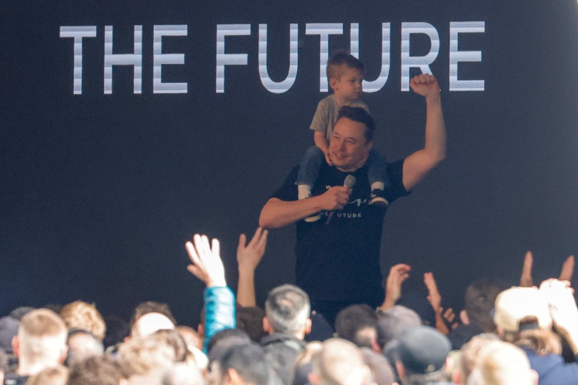 Tesla CEO Elon Musk enters the stage with a child on his shoulders at the Tesla Gigafactory for electric cars in Gruenheide near Berlin, Germany, Wednesday, March 13, 2024. Power has been restored to electric car manufacturer Tesla's factory near Berlin about a week after an outage believed to have been caused by arson, a network operator says. (Carsten Koall/dpa via AP) Tesla CEO Elon Musk enters the stage with a child on his shoulders at the Tesla Gigafactory for electric cars in Gruenheide near Berlin, Germany, Wednesday, March 13, 2024. Power has been restored to electric car manufacturer Tesla's factory near Berlin about a week after an outage believed to have been caused by arson, a network operator says. (Carsten Koall/dpa via AP)