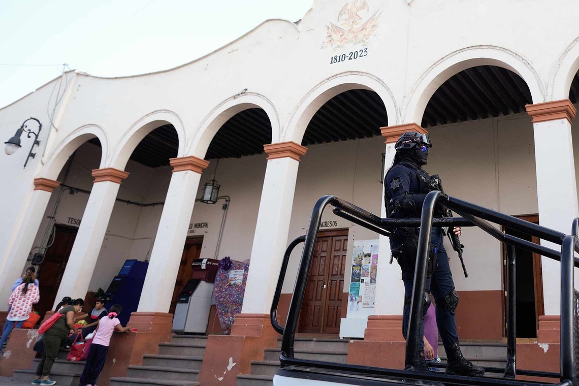 En tungt væpnet politimann kjører forbi rådhuset i Maravatio, delstaten Michoacan, Mexico, tirsdag 27. februar 2024, i et politikjøretøy. To ordførerkandidater i denne byen ble skutt ned dagen før med bare noen timers mellomrom. (Foto: Fernando Llano, AP Photo.) Politimann i Mexico