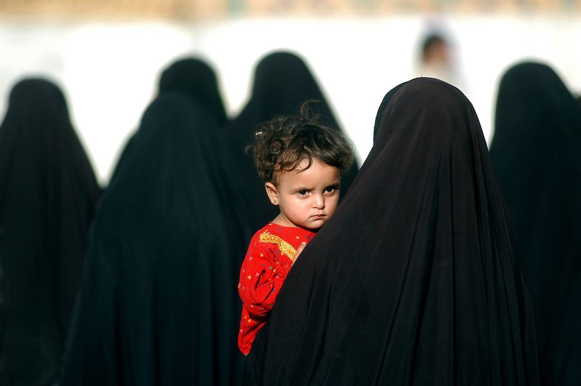 Little girl in red worn by a woman in hijab, Karbala, Iraq, 19.08.2003. Photo: Shutterstock by Veselin Borishev. Little girl in red worn by a woman in hijab, Karbala, Iraq, 19.08.2003. Photo: Shutterstock by Veselin Borishev.