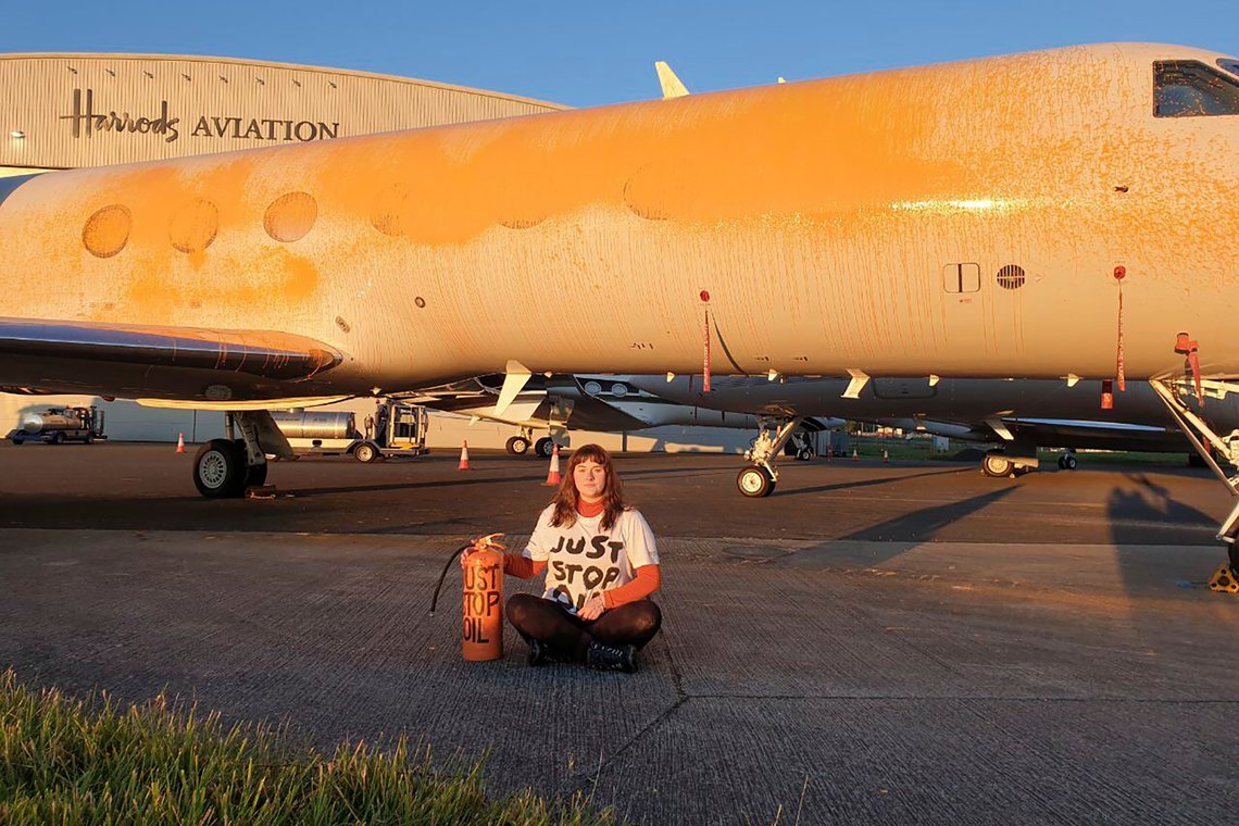 En aktivist fra protestgruppa Just Stop Oil poserer ved siden av et privatfly spraymalt med oransje maling på Stansted lufthavn i Storbritannia 20. juni. Britisk politi har pågrepet 27 aktivister fra protestgruppa for planer om å forstyrre flytrafikken ved britiske flyplasser i sommer. Foto: Just Stop Oil / AP / NTB En aktivist fra protestgruppa Just Stop Oil poserer ved siden av et privatfly spraymalt med oransje maling på Stansted lufthavn i Storbritannia 20. juni. Britisk politi har pågrepet 27 aktivister fra protestgruppa for planer om å forstyrre flytrafikken ved britiske flyplasser i sommer. Foto: Just Stop Oil / AP / NTB