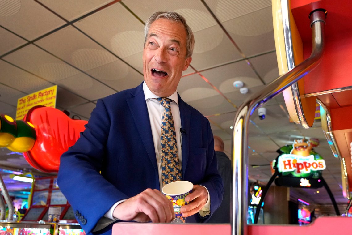 Britain's Nigel Farage, Reform UK party leader plays on a game in an amusement arcade holds out some coins whilst spending time with supporters in Clacton-On-Sea, Essex, England Friday, June 21, 2024. (AP Photo/Kirsty Wigglesworth) Britain's Nigel Farage, Reform UK party leader plays on a game in an amusement arcade holds out some coins whilst spending time with supporters in Clacton-On-Sea, Essex, England Friday, June 21, 2024. (AP Photo/Kirsty Wigglesworth)
