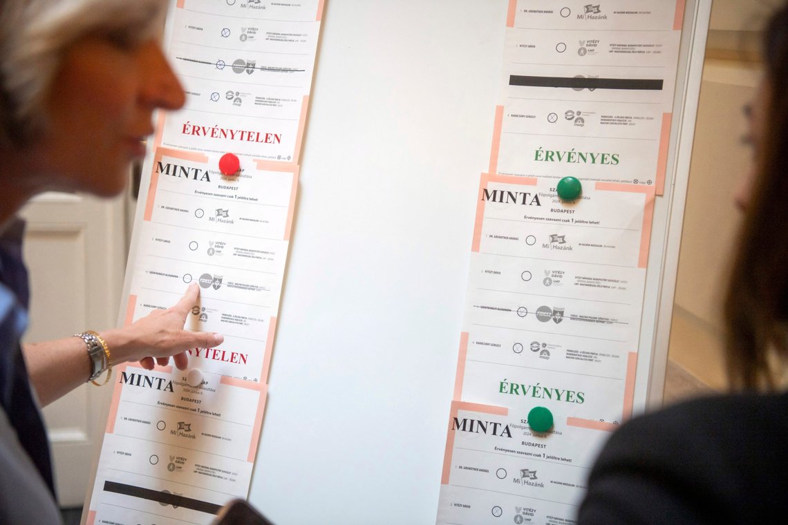 En tjenestemann viser til merkede stemmesedler under omtellingen av ugyldige stemmer avgitt ved borgermestervalget i Budapest 9. juni, fredag 14. juni 2024, ved det nasjonale valgkontoret (NVI) i Budapest, Ungarn. NVI-tjenestemenn leter etter gyldige stemmer som feilaktig er klassifisert som ugyldige, ved å inspisere stemmesedler med mer enn ett kryss. Den sittende borgermesteren Gergely Karacsony, kandidaten til alliansen Dialog-Grønne-Demokratisk koalisjon-Sosialistene, vant valget, men andreplassen, David Vitezy, kandidaten til opposisjonspartiet LMP og en borgerbevegelse, tok initiativ til en ny opptelling på grunn av en systemfeil som førte til et rekordhøyt antall ugyldige stemmer i det usedvanlig tette løpet om ordførervervet i Budapest. (Zoltan Balogh/MTI via AP) En tjenestemann viser til merkede stemmesedler under omtellingen av ugyldige stemmer avgitt ved borgermestervalget i Budapest 9. juni, fredag 14. juni 2024, ved det nasjonale valgkontoret (NVI) i Budapest, Ungarn. NVI-tjenestemenn leter etter gyldige stemmer som feilaktig er klassifisert som ugyldige, ved å inspisere stemmesedler med mer enn ett kryss. Den sittende borgermesteren Gergely Karacsony, kandidaten til alliansen Dialog-Grønne-Demokratisk koalisjon-Sosialistene, vant valget, men andreplassen, David Vitezy, kandidaten til opposisjonspartiet LMP og en borgerbevegelse, tok initiativ til en ny opptelling på grunn av en systemfeil som førte til et rekordhøyt antall ugyldige stemmer i det usedvanlig tette løpet om ordførervervet i Budapest. (Zoltan Balogh/MTI via AP)
